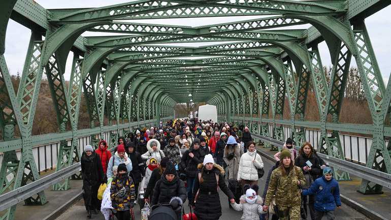 Українські біженці йдуть мостом на кордоні з Польщею 6 березня