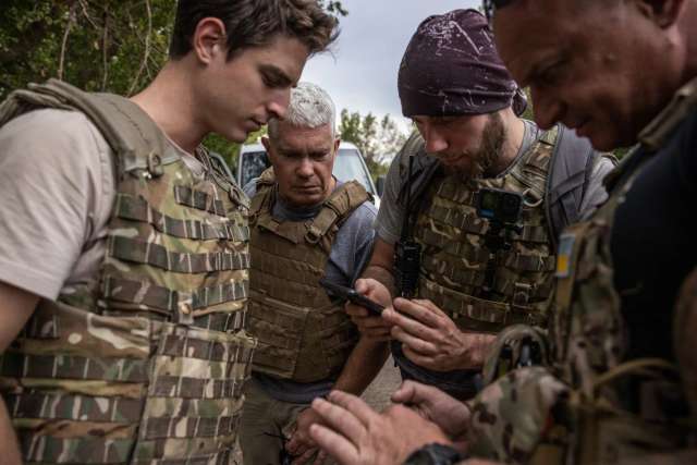 Ендрю Мілберн, у центрі, переглядає адреси можливих евакуйованих із волонтерами перед тим, як відправитися на фронт на сході України минулого літа.