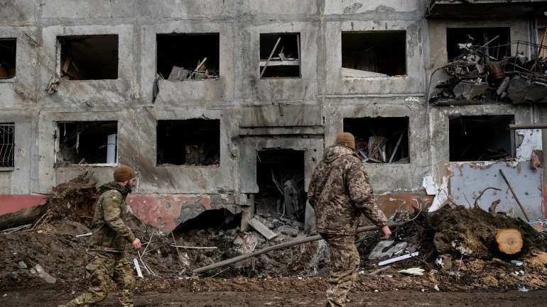 Українські військові йдуть повз воронку перед багатоповерховим будинком у неділю, через день після ракетного обстрілу в Дружківці на сході України.