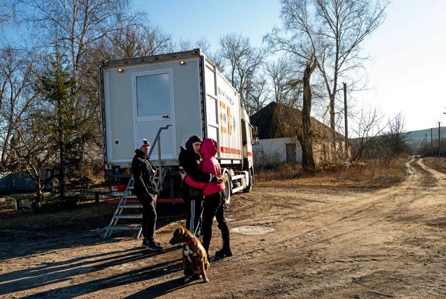 Пара обіймається в очікуванні лікаря в пересувній медичній вантажівці в Харківській області. Хоча війна недалека від думок людей, більшість селян зайняті більш повсякденними турботами.