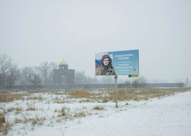 Плакат із зображенням російського солдата з гаслом «Слава Героям росії» видно на дорозі біля каплиці, побудованої в пам'ять про бійців Вагнера.