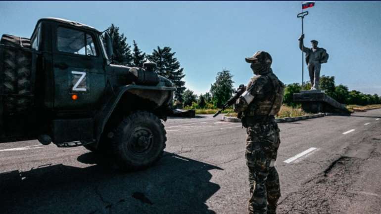 Російський солдат стоїть біля пам'ятника металургам на в'їзді в окупований Маріуполь, 12 червня 2022 року.